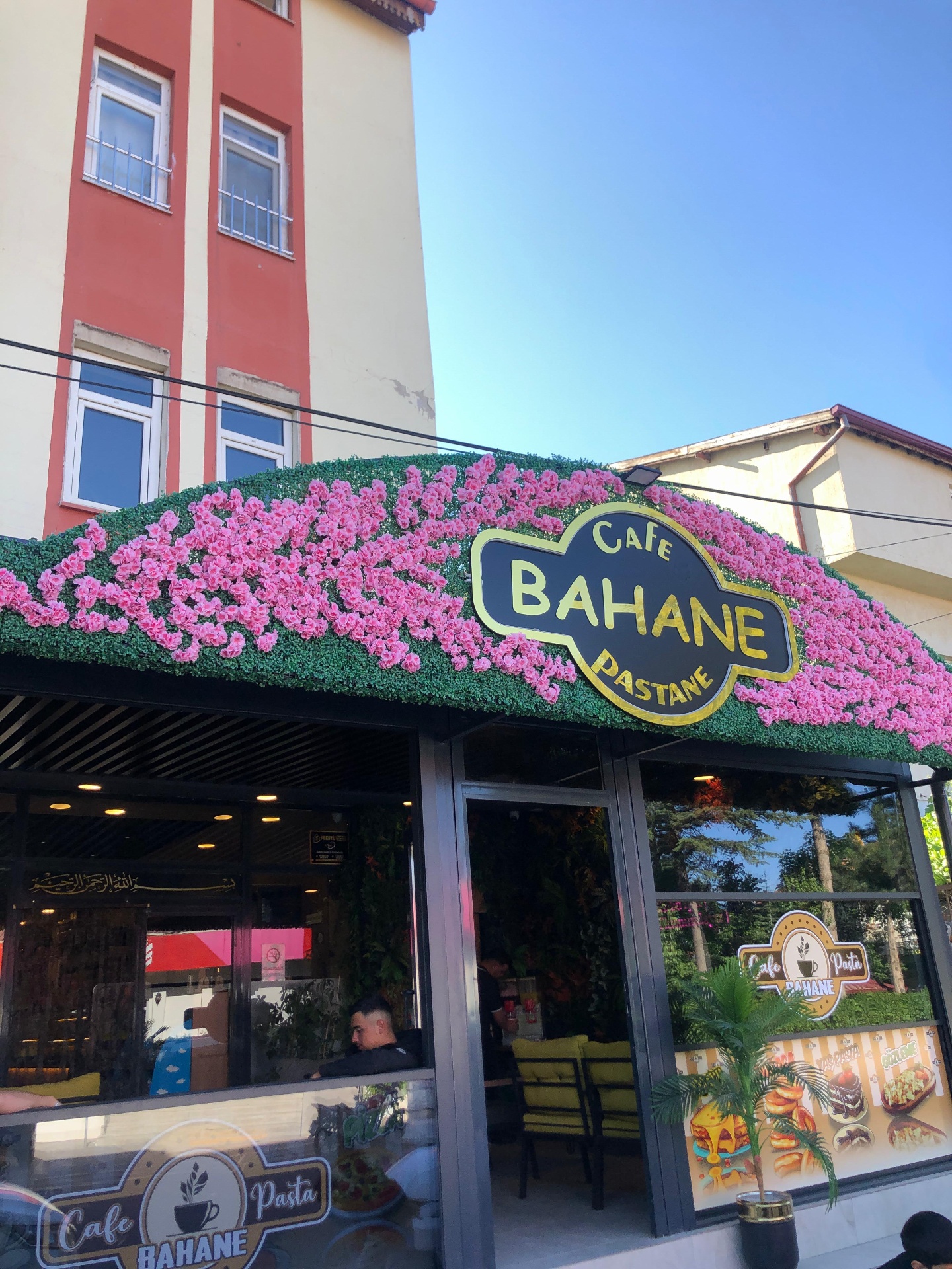 Bahane Cafe dış cephesi — yeşil tabela ve pembe çiçekler